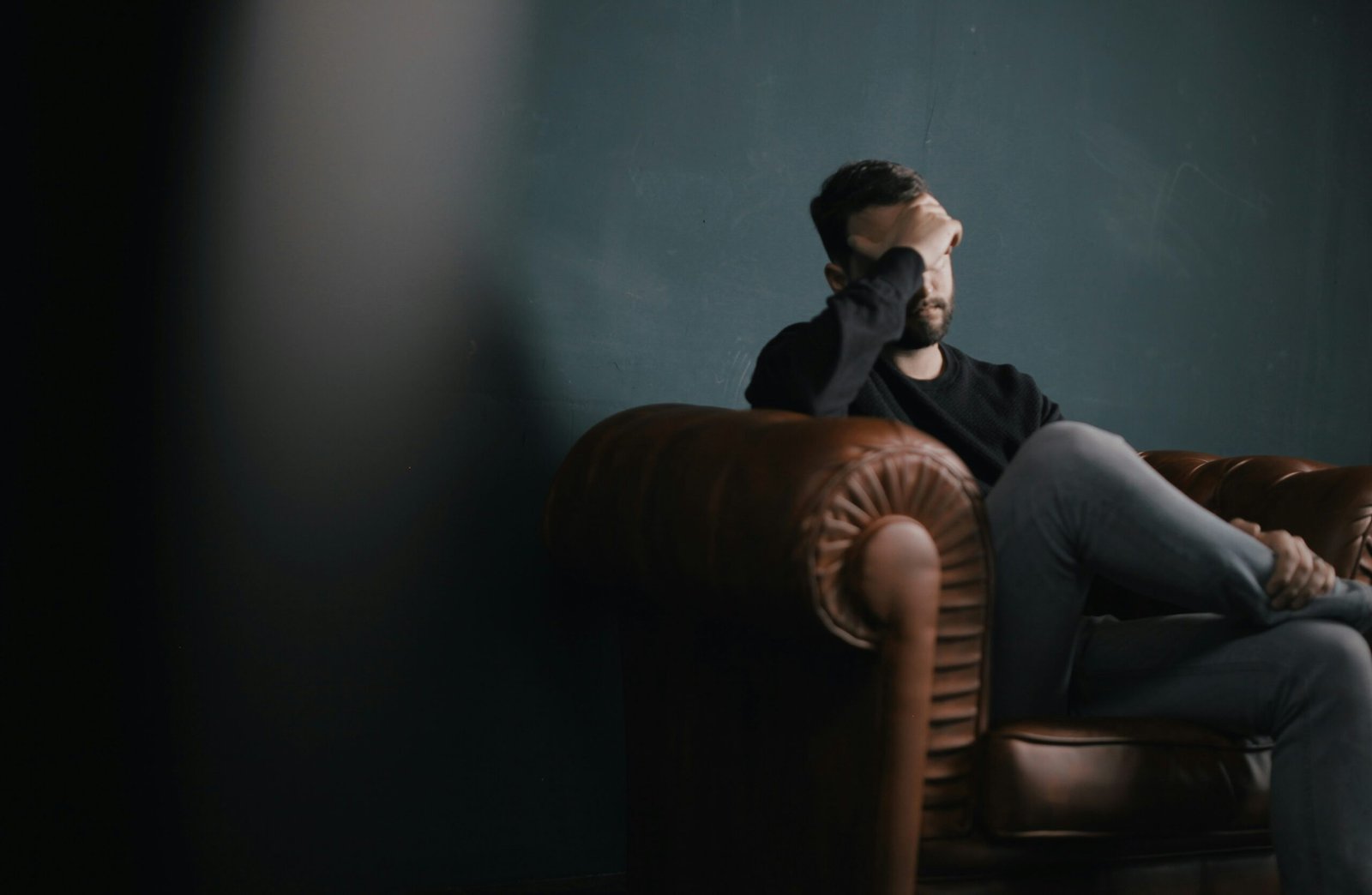 a depressed man holds his head while sitting on a sofa