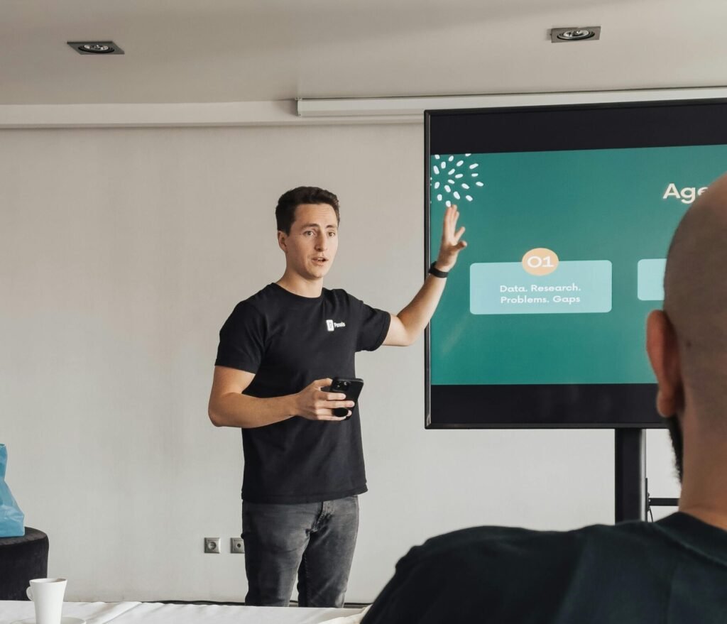 Young man presenting to a group in front of a screen